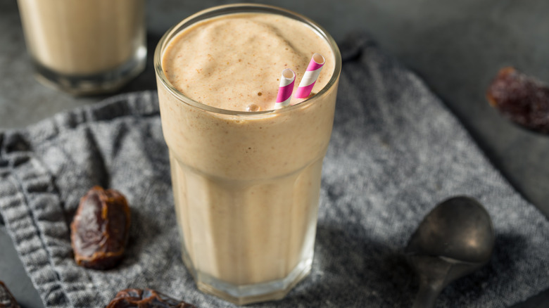 a date milkshake with two red striped straws