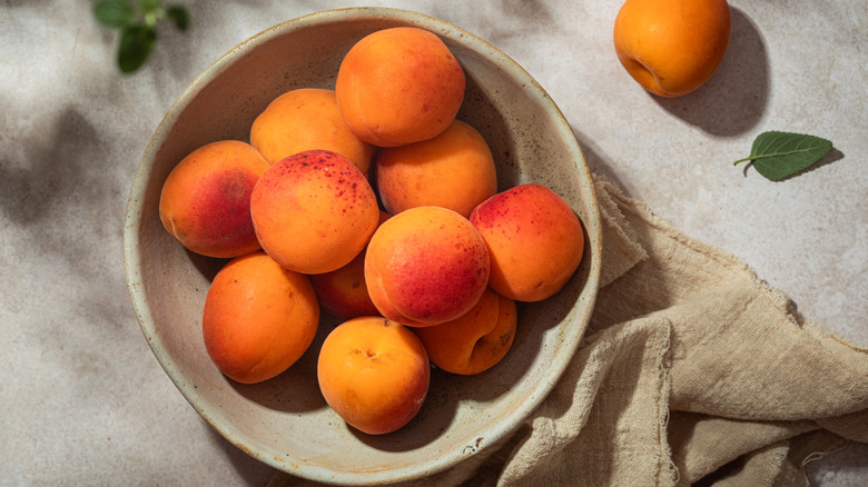 Several apricots in a stoneware bowl