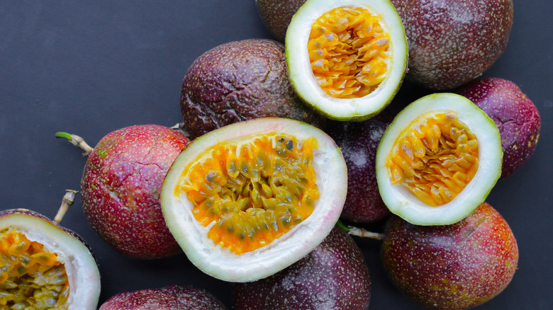 Sliced passion fruit with bright purple exterior and seedy, yellow-orange interior