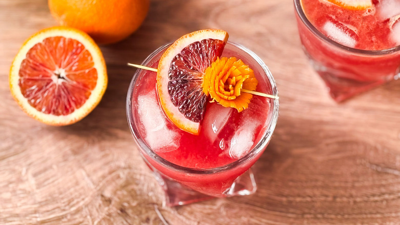 Fresh and fruity blood orange cocktail with citrus garnish in rocks glass with cut blood orange half