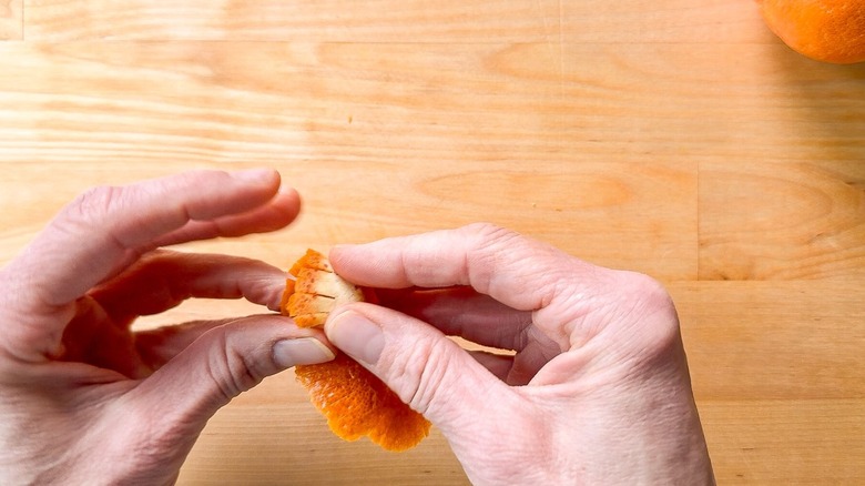Rolling up strip of blood orange zest with fingers