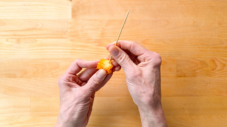 Pushing a wooden pick into rolled up blood orange zest