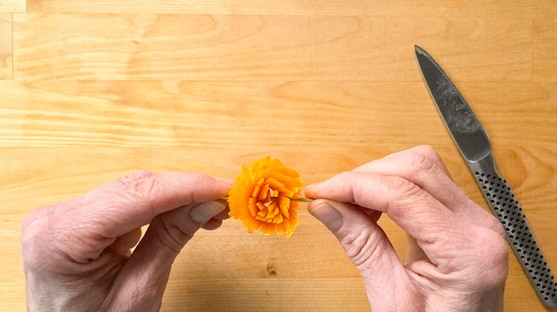 Holding blood orange zest frill garnish on wooden pick