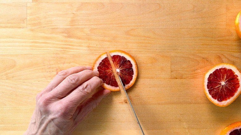 Cutting a blood orange slice on a cutting board