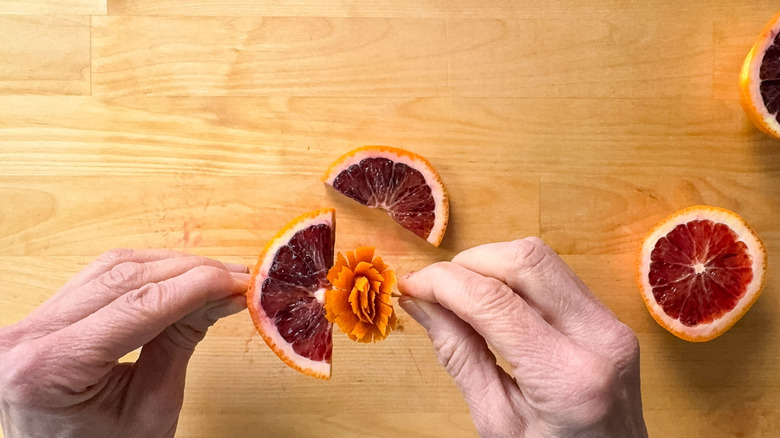 Orange zest frill and blood orange half slice on wooden pick