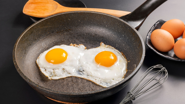 Two eggs are seen frying in a pan.