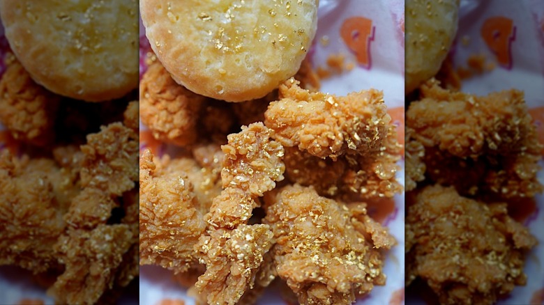 Close-up of Popeyes chicken and biscuit with gold flakes.