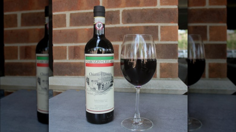 A bottle and a glass of Chianti Classico sitting side by side.