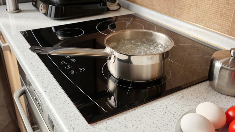 Boiling water in a metal ladle on an induction cooker against the background of a kitchen, cooking at home