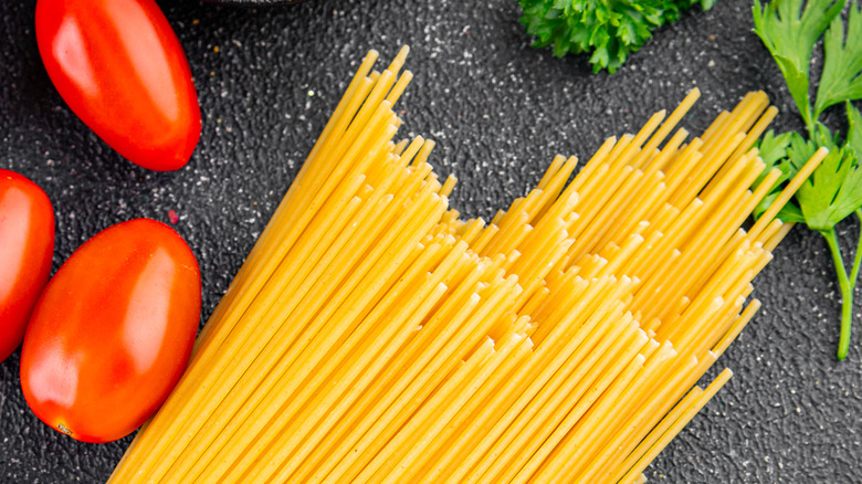dry spaghetti noodles next to cherry tomatoes