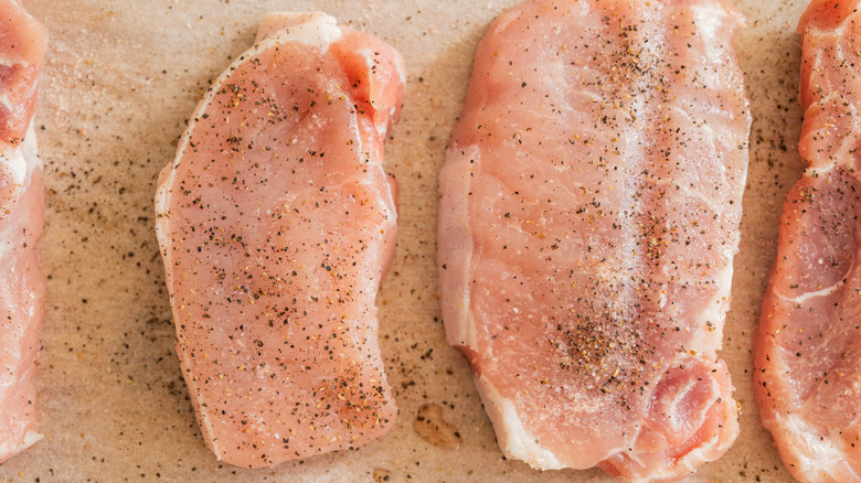 Pork chops coated in salt and pepper on parchment
