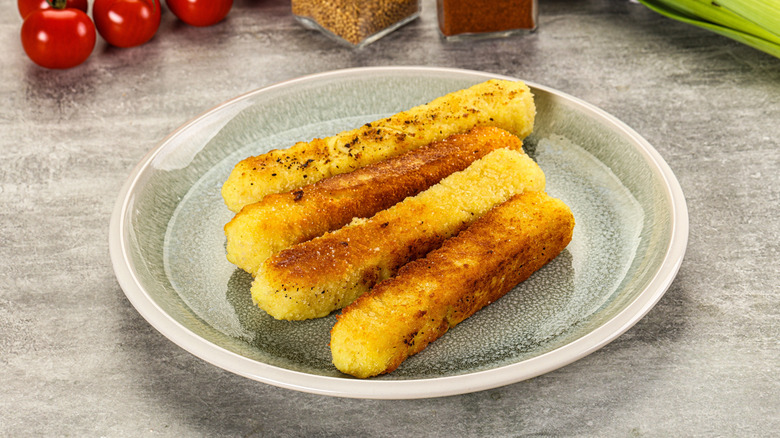 A plate with crispy breaded mozzarella sticks.