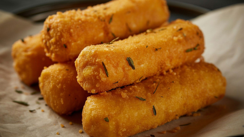 Golden fried mozzarella sticks on parchment paper.