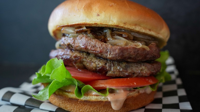 A juicy burger with tomatoes, lettuce and onions.