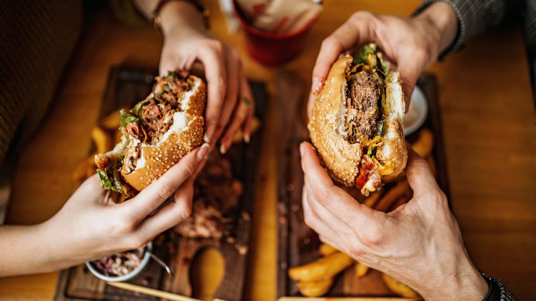 Two sets of hands holding burgers