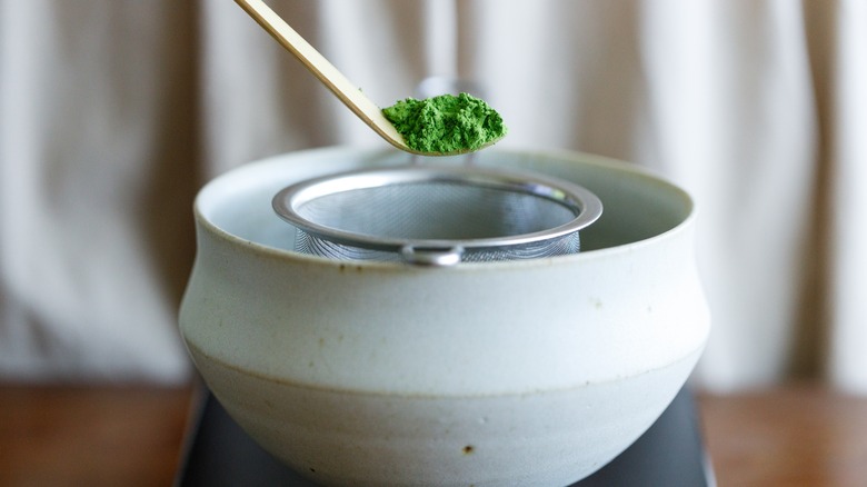 Closeup of matcha powder being added to a bowl
