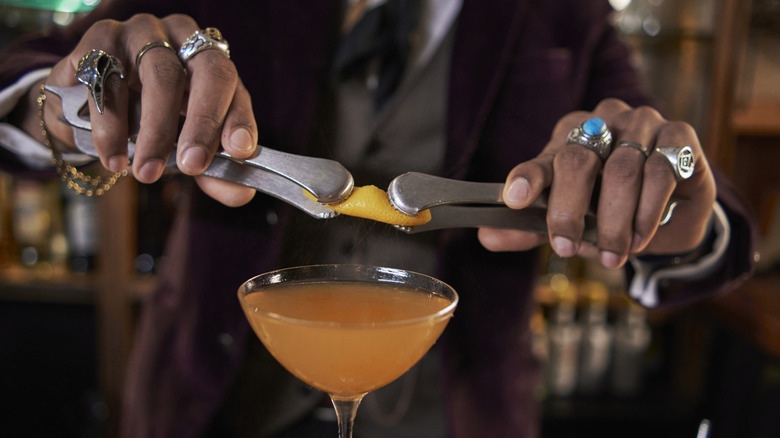 a person wearing rings making a cocktail