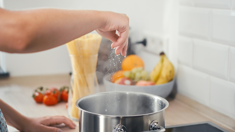 Woman salting boiling water