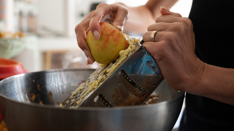 hand grating apple into a bowl