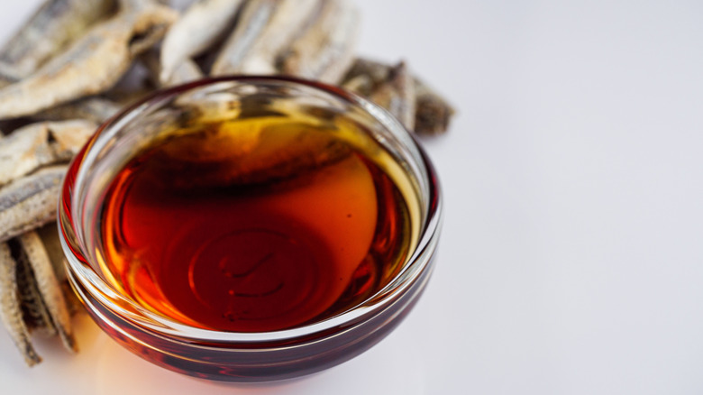 A small bowl of fish sauce next to anchovies