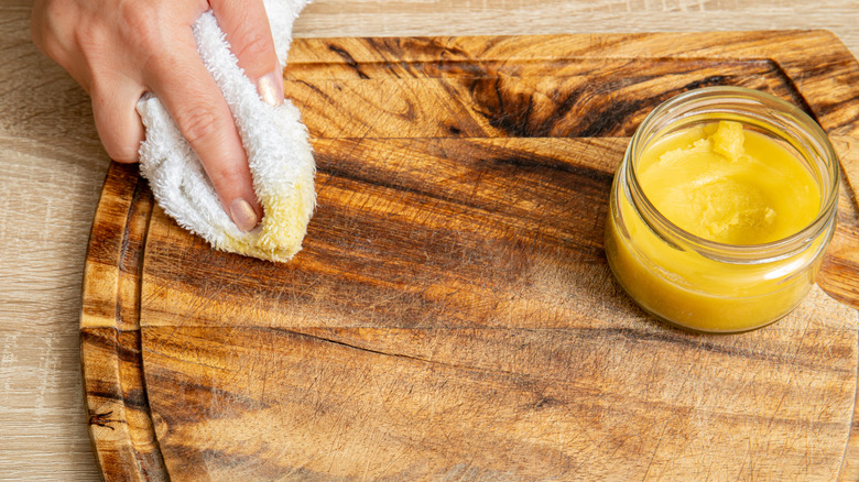 woman applying wood conditioner to a cutting board