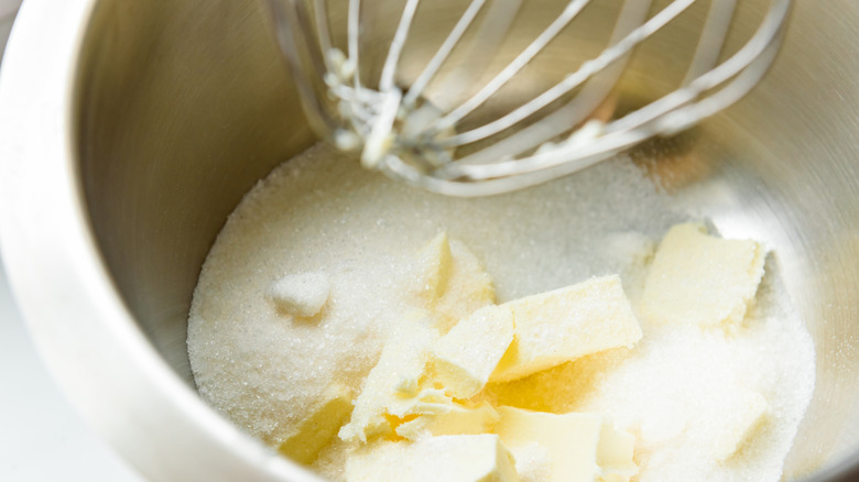 Butter and sugar in a bowl with whisk above