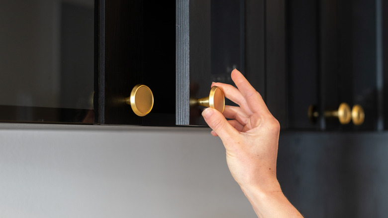 A hand pulling a cabinet knob