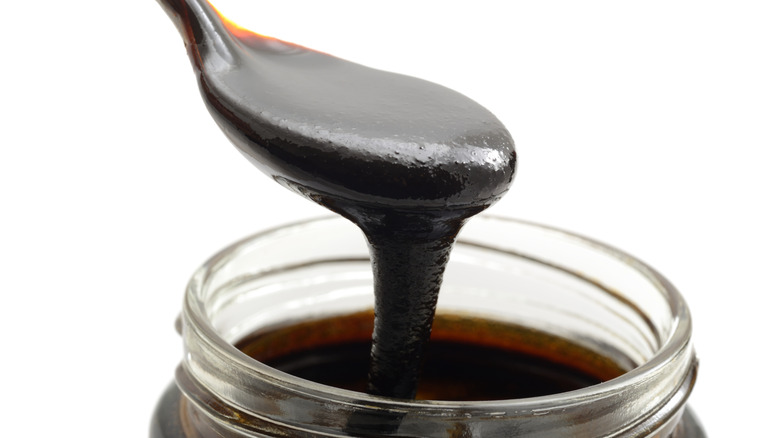 Molasses pouring from spoon into jar