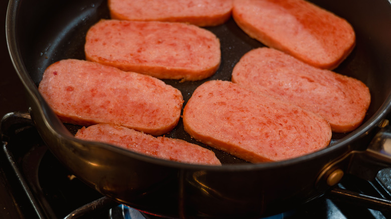 Slices of Spam in a black frying pan