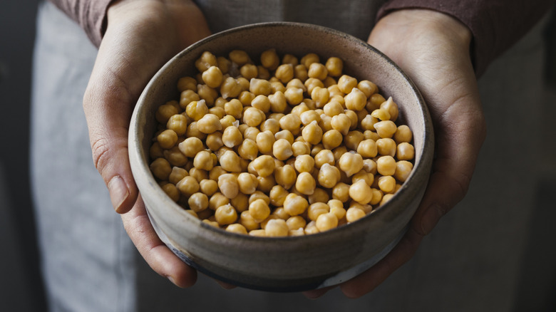 A closeup of hands holding a bowl of chickpeas