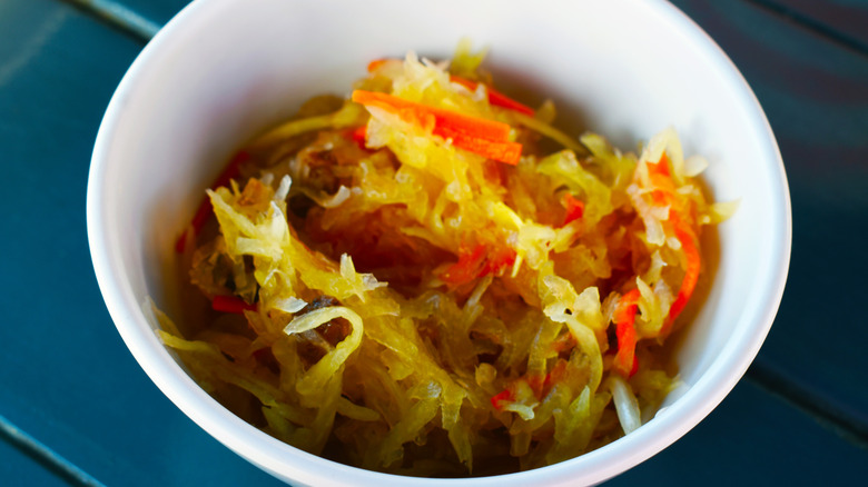 Atchara in a white bowl, with shreds of carrots and papaya