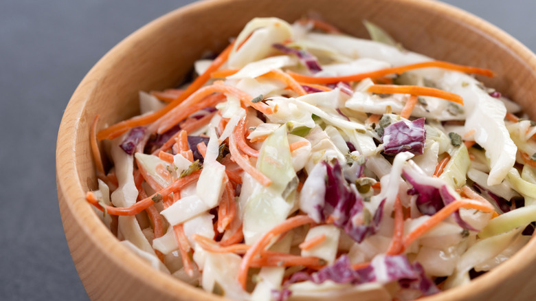 A wooden bowl of colorful coleslaw.
