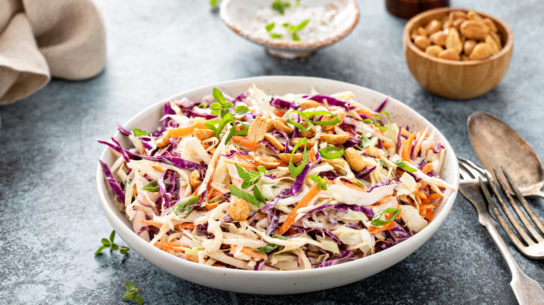 Coleslaw in a white bowl topped with peanuts