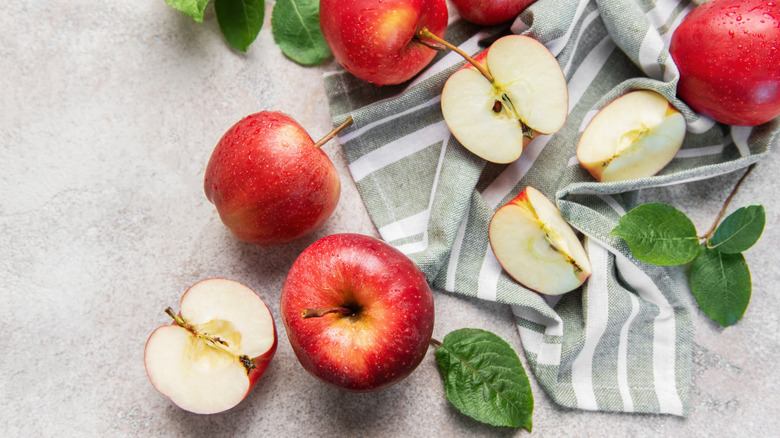 Whole, halved, and quartered apples are photographed from above.