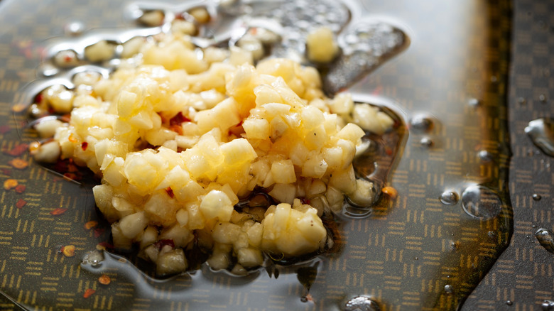 Close-up of minced garlic being fried in butter with red pepper flakes