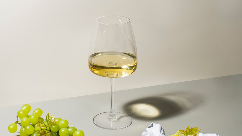 A glass of white wine on a light gray surface.