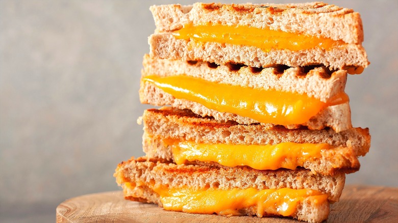 Stack of halved, panini-pressed grilled cheese sandwiches on a wooden serving board