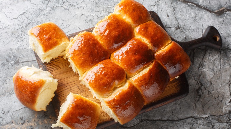 A fresh batch of Hawaiian rolls arranged on a wooden board.