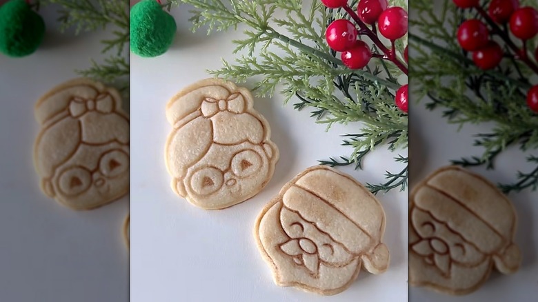 Cookies with stamped designs highlighted using cocoa powder sitting next to fake mistletoe.