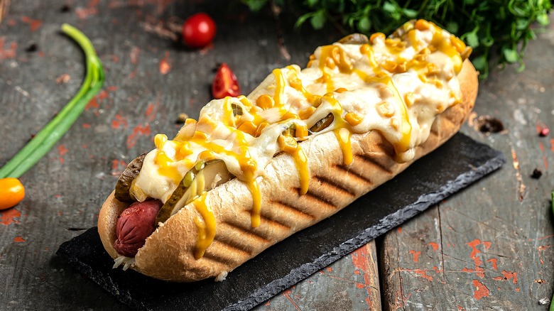 Hot dog topped w pickles, corn, melted cheese, and mustard