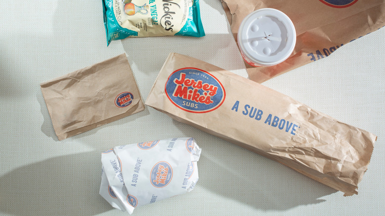 An overhead shot of a wrapped Jersey Mike's sub with potato chips and napkins.
