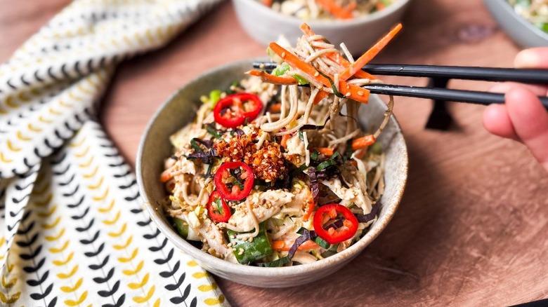 Picking up a bite of chilled soba salad with leftover rotisserie chicken in serving bowl with chopsticks
