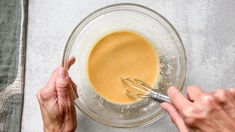 Whisking the dressing for chilled soba salad in glass bowl