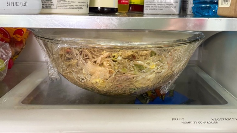 Chilled soba salad with leftover rotisserie chicken in covered glass bowl in refrigerator