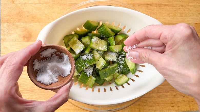 Salting cucumber slices in colander