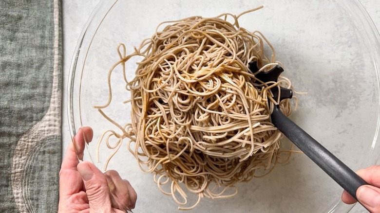 Cooked soba noodles in large glass bowl with black spoon