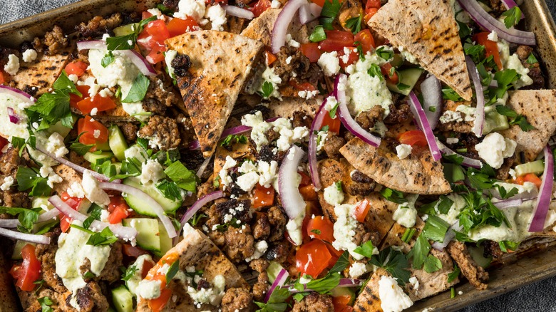 A platter filled with pita triangles and ingredients typically found in Greek salad.
