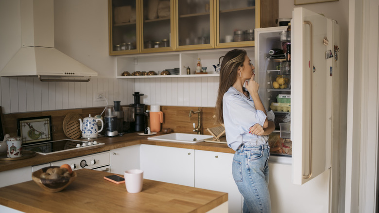 A person is seen looking into a refrigerator.