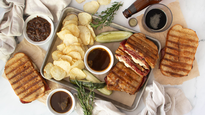 French dip pastrami sandwiches with au jus and chips