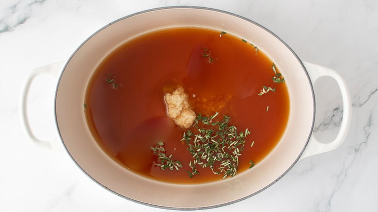 Broth, horseradish and herbs in large pot